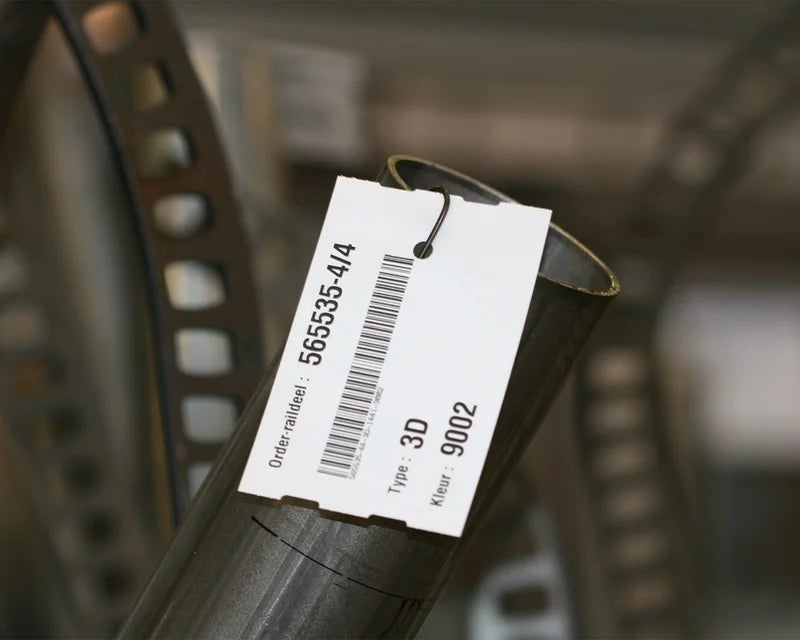 Witte hittebestendige tag met barcode en ordergegevens bevestigd aan stalen buis