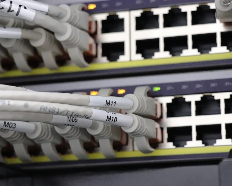 Witte kabellabels met poortcodes op witte netwerkkabels aangesloten op netwerkswitch