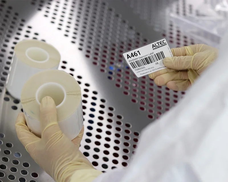 Medewerker brengt cleanroom label aan op een rol labels in een steriele omgeving.