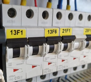 Gele componentlabels met coderingen aangebracht op installatieautomaten in elektrische verdeelkast