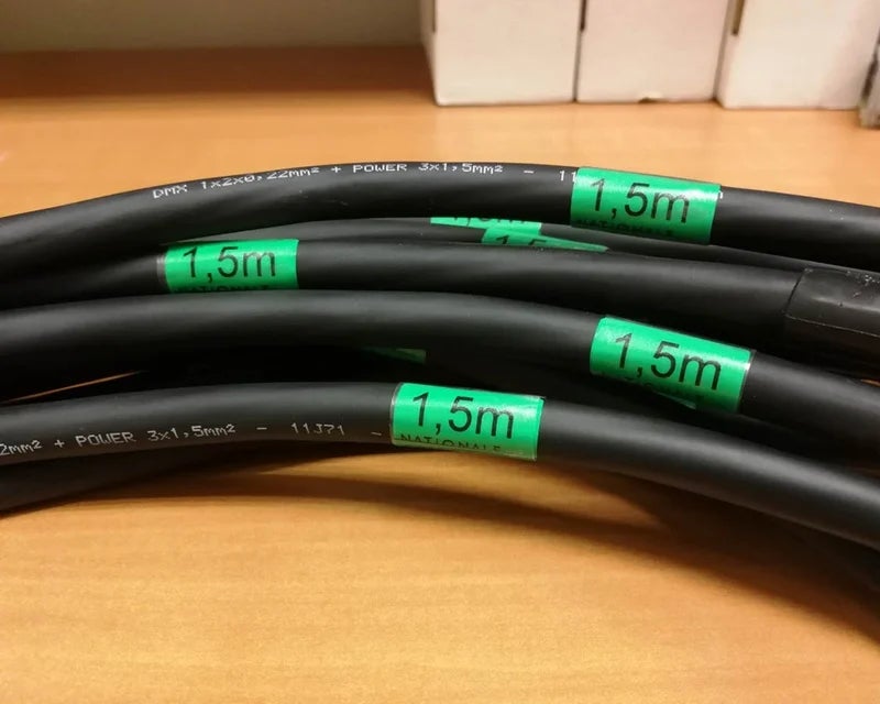 Groene wikkellabels met kabellengte op zwarte kabels voor kabelbeheer