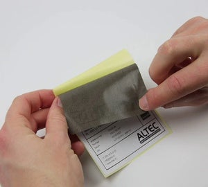 Hand verwijdert een correctielabel van de drager, klaar om een oud of foutief verzendlabel af te dekken