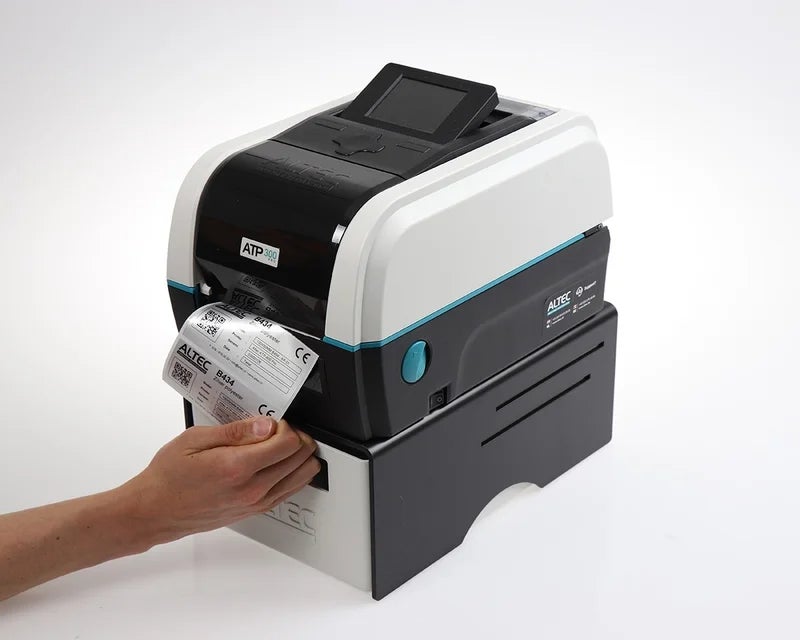 Gebruiker haalt een geprint polyester label uit de ATP-300 Pro labelprinter