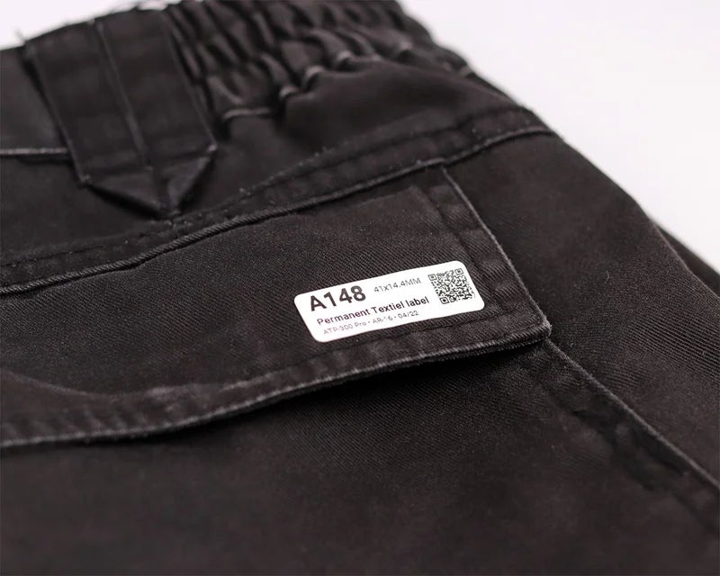 Permanent kledinglabel met QR-code bevestigd op zwarte werkbroek