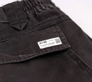 Permanent kledinglabel met QR-code bevestigd op zwarte werkbroek