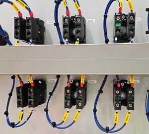 Gele wire tags met adercodes op blauwe aders bij componenten in schakelkast