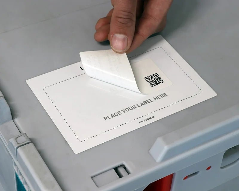 Hand verwijdert een label uit het Place Label Here op een kunststof bak