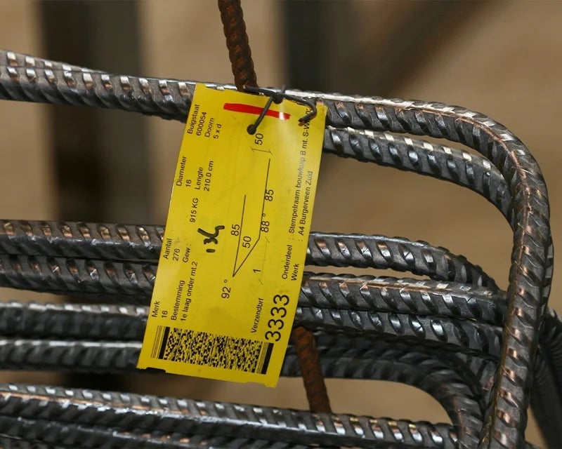 Gele industriële tag met technische gegevens bevestigd aan een wapeningskorf