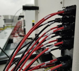 Witte wikkellabels met stringnummers op rode en zwarte PV-kabels bij zonne-energie installatie
