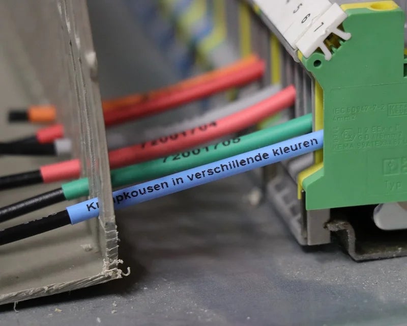 Gekleurde krimpkous op zwarte aders bij klemmenstrook