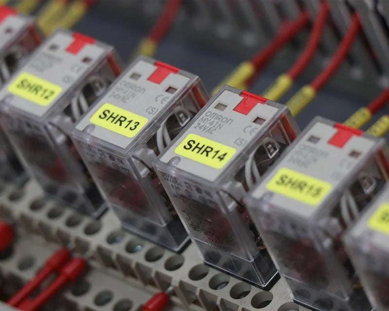 Gele componentlabels met identificatiecodes aangebracht op relaismodules in schakelkast